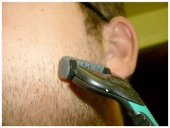 A man dry shaving near his ear with a cartridge razor